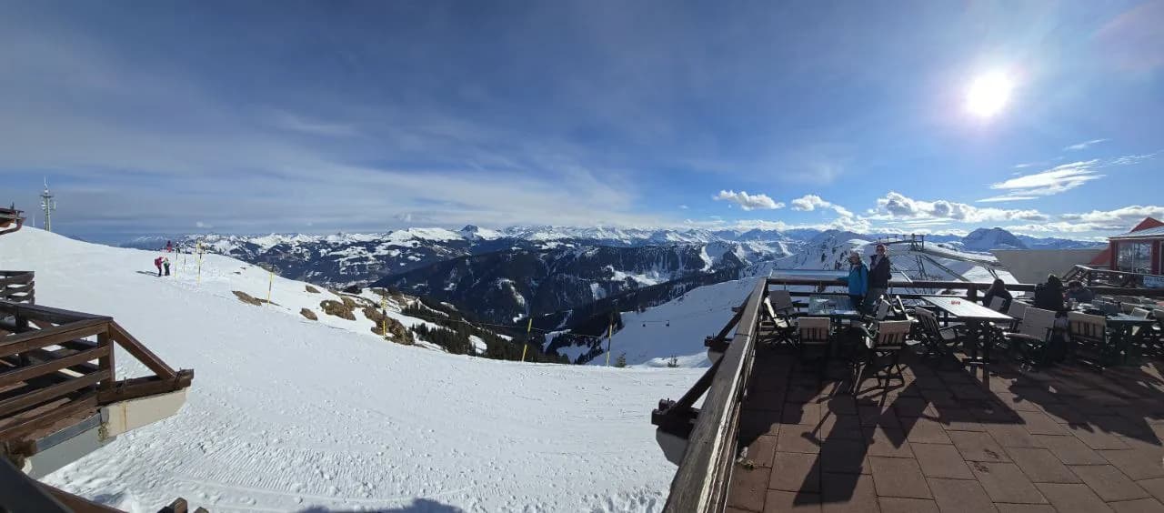 Hüttenterrasse im Schnee mit weitem Bergpanorama im Gegenlicht
