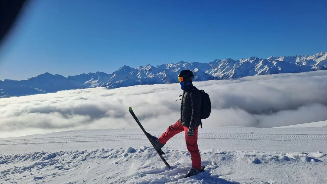 Ein Skifahrer steht auf einem Grat über einem Wolkenmeer