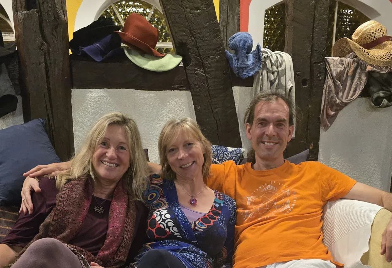 Gerald sitzt lächelnd mit zwei Mitveranstalterinnen auf einem Sofa
