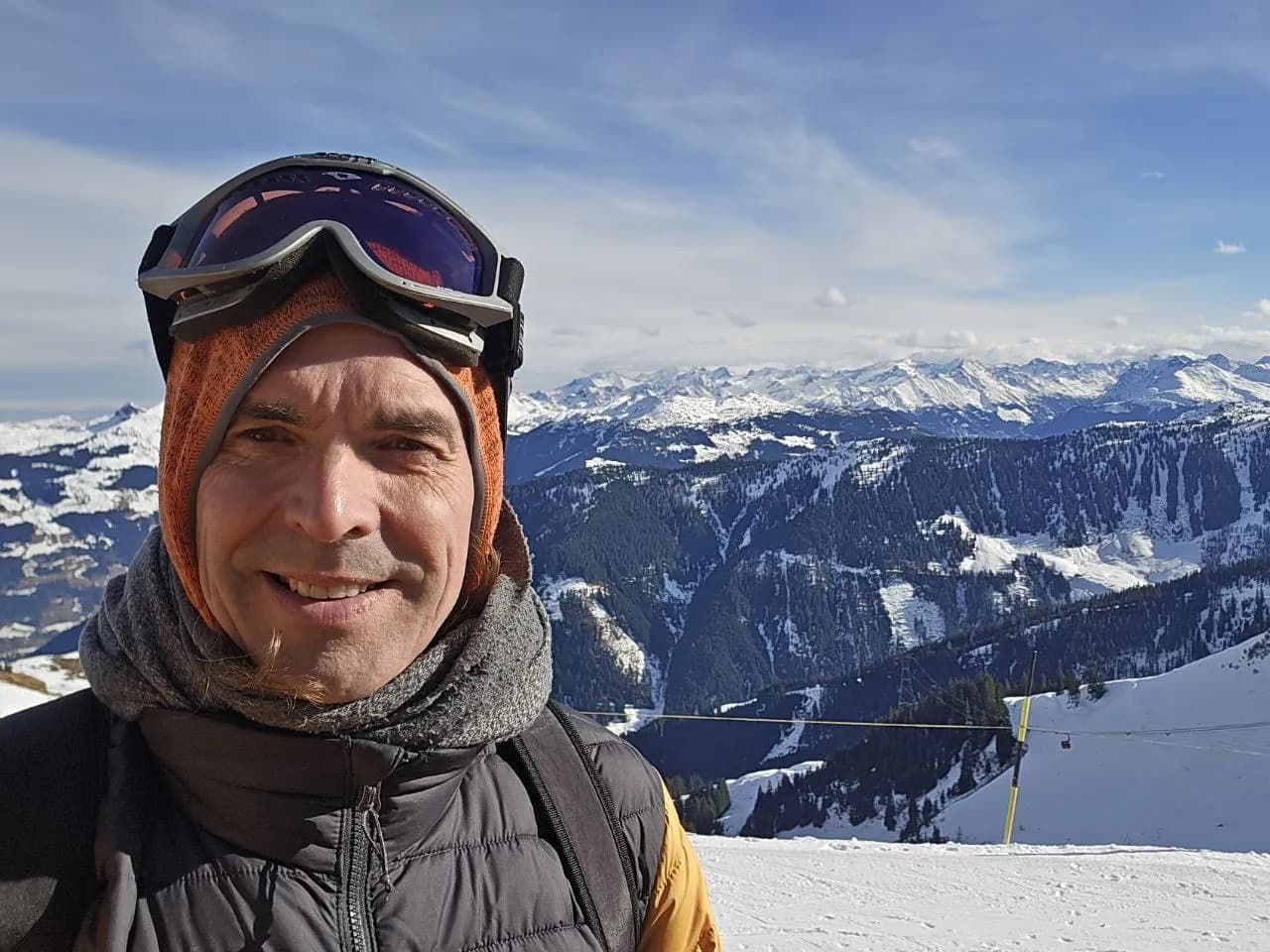 Gerald mit Skibrille und Mütze, hinter ihm verschneite Berge