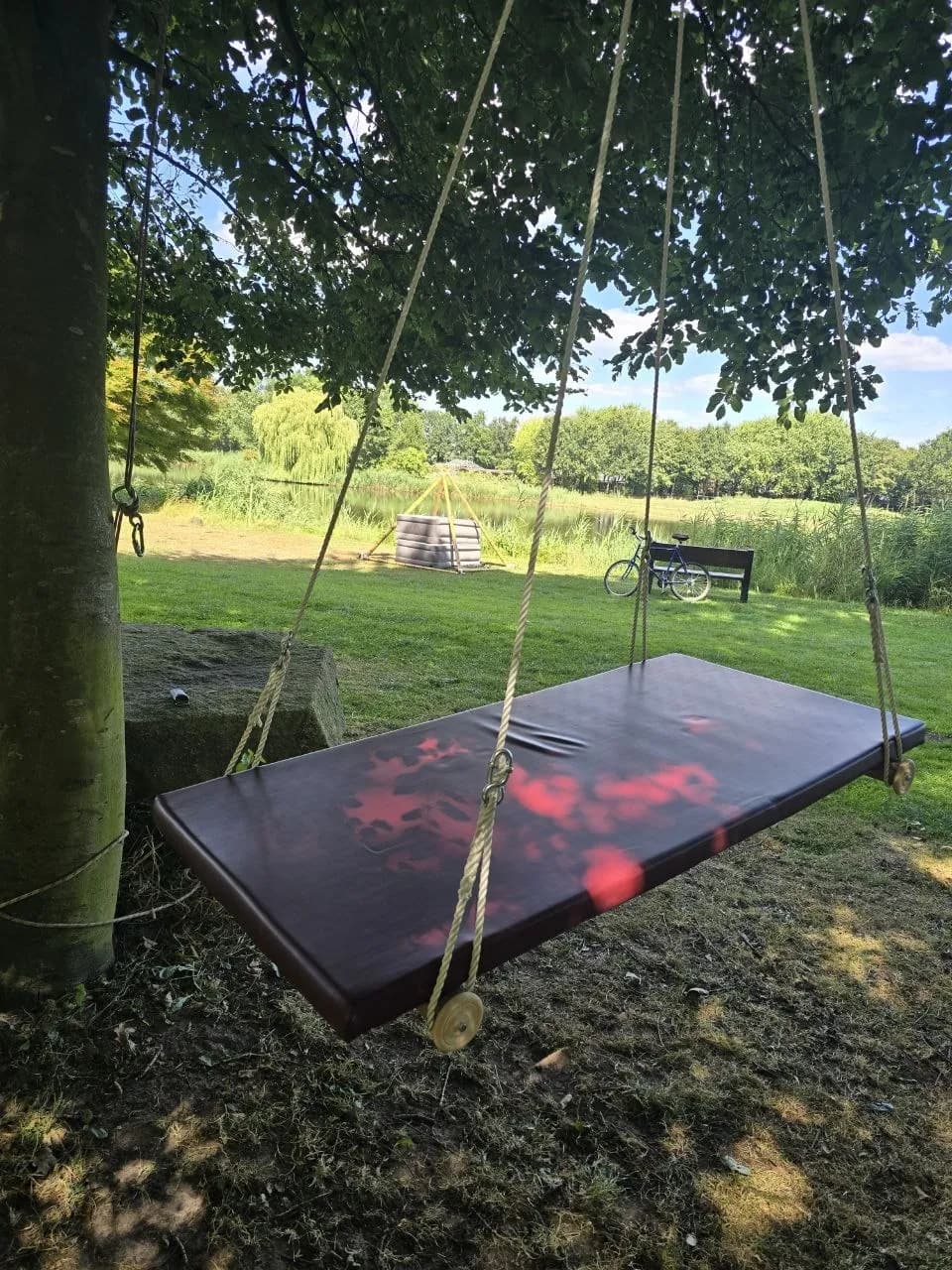 Die Schwebeliege Swing Star, an einem Baum über einem Teich aufgehängt